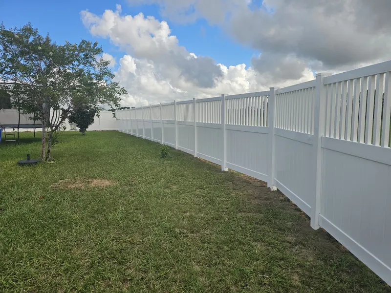 White vinyl privacy fence with picket top running along a Florida backyard