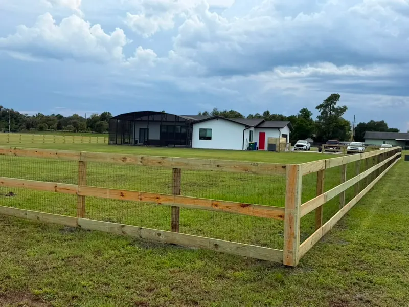 Three-rail wood ranch fence with wire mesh enclosing a pasture in Central Florida