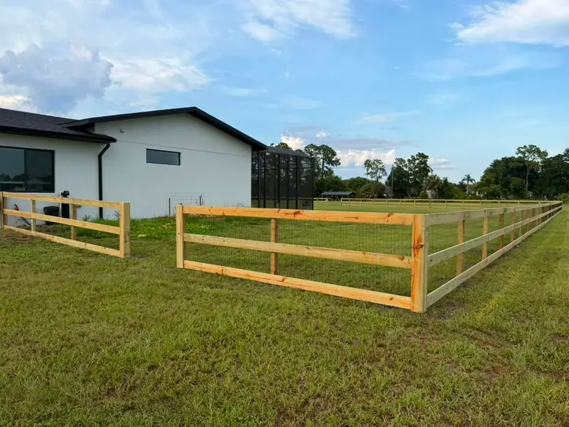 Three-rail ranch fence with wire backing and gate section around a rural Florida home
